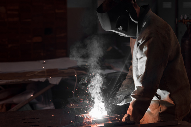 soldador en máscara de protección que trabaja con metal en fábrica
  - Foto, imagen