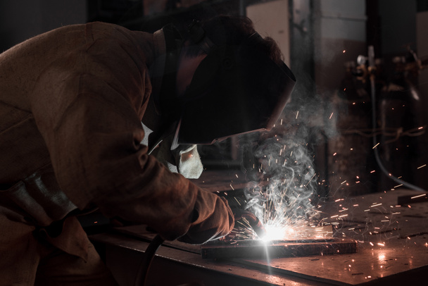 vista lateral del trabajador en metal de soldadura máscara de protección en fábrica
  - Foto, Imagen