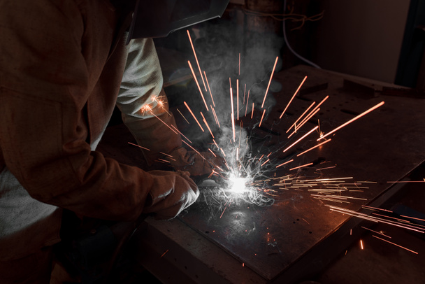 imagen recortada de soldador en máscara de protección que trabaja con metal en fábrica
  - Foto, Imagen