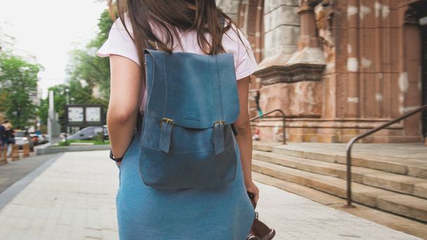 Rear view image of stylish tourist girl with bag walking on old street - Zdjęcie, obraz