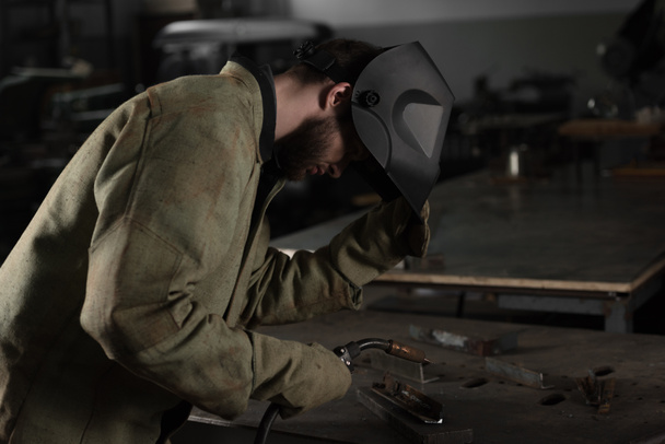 soldador levantando máscara protectora para ver su trabajo en la fábrica
 - Foto, imagen