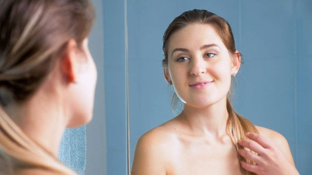 Портрет красивой брюнетки, позирующей в ванной комнате перед зеркалом
 - Фото, изображение