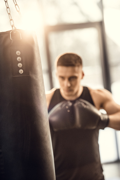 selective focus of athletic young man boxing with punching bag - Foto, Imagem