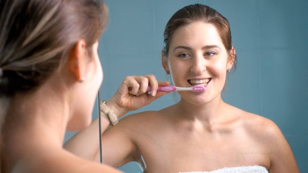 Фото счастливой улыбающейся женщины, чистящей зубы в ванной комнате
 - Фото, изображение