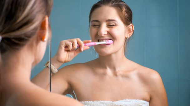 Photo of happy smiling woman cleaning teeth in morning at bathroom - Zdjęcie, obraz