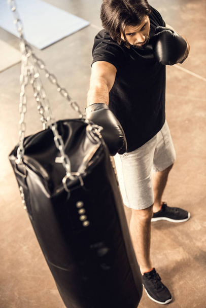 high angle view of sporty young man boxing with punching bag in gym  - Φωτογραφία, εικόνα