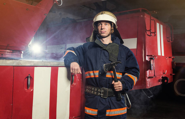 Pompiere (pompiere) in azione in piedi vicino a un camion dei pompieri. Emer
 - Foto, immagini