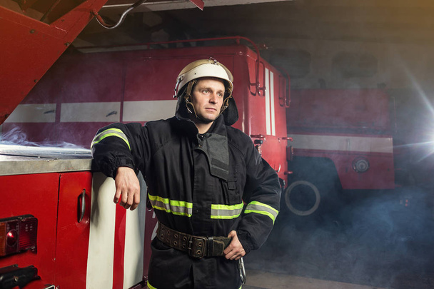 Fireman (firefighter) in action standing  near a firetruck. Emergency safety. Protection, rescue from danger. - Foto, Bild