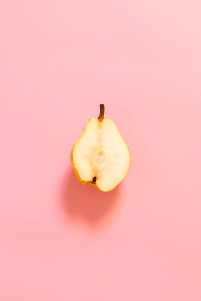 Μισό από το cut κίτρινο αχλάδι σε μια παστέλ ροζ φόντο. - Φωτογραφία, εικόνα