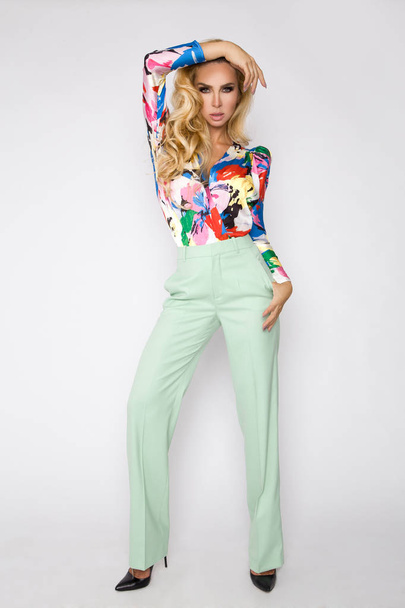 Beautiful woman with long blond hair, dressed in colorful, spring clothing with flowers pattern. - Фото, изображение