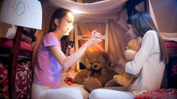 Mädchen im Pyjama erschreckt Freundin nachts mit gruseliger Geschichte - Foto, Bild