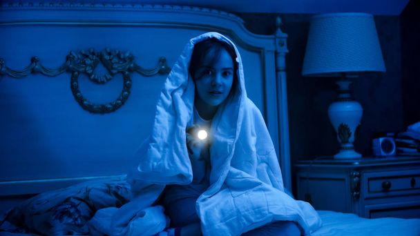 Genç kız battaniye içinde karanlık yatak odasında el feneri ile örtülü - Fotoğraf, Görsel