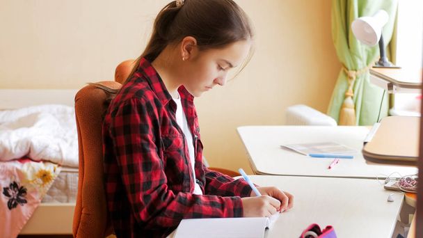 Portret van tienermeisje huiswerk in slaapkamer - Foto, afbeelding