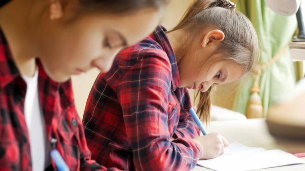 Portrait de concentrée 10 ans fille faire des devoirs avec sœur
 - Photo, image