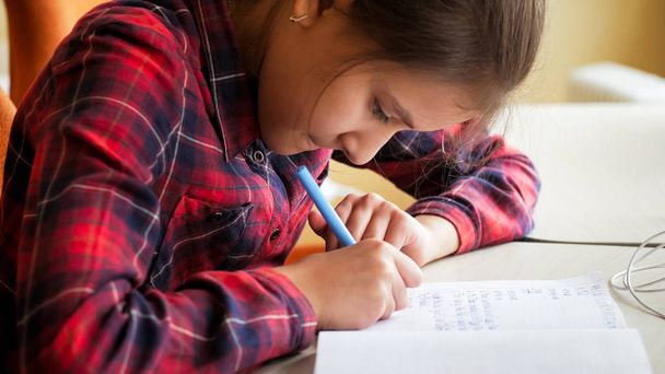 Toned photo of girl writing in copybook with ink pen - Foto, Bild