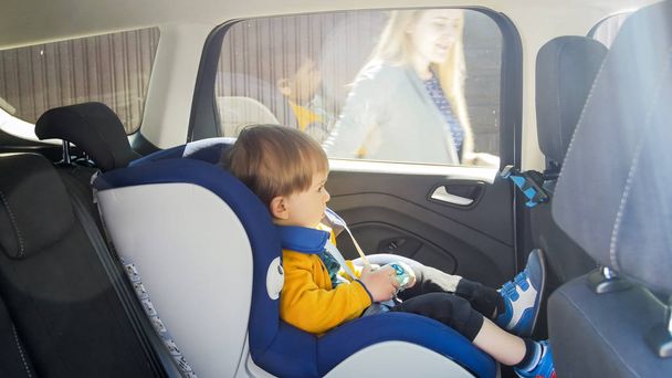 Bonito menino criança sentado no assento de segurança do carro
 - Foto, Imagem