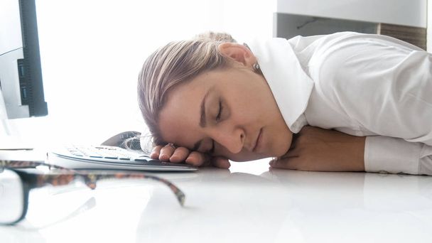 Foto de primer plano de la joven empresaria sobrecargada de trabajo se quedó dormida en el lugar de trabajo
 - Foto, Imagen