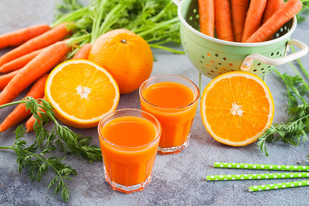 Zumo fresco de zanahoria y naranja en la mesa gris - comida y bebida
 - Foto, imagen