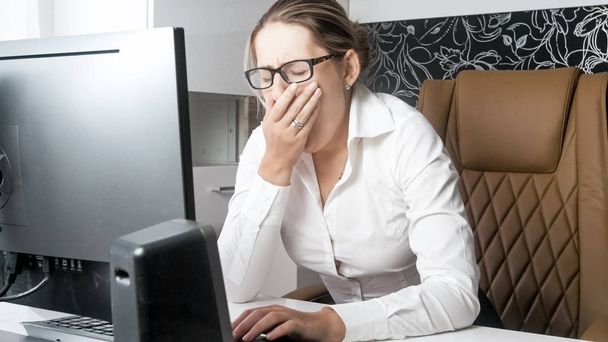 Портрет измученной деловой женщины, зевающей во время работы в офисе
 - Фото, изображение
