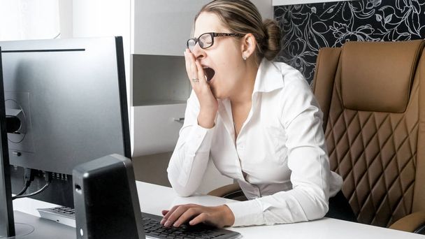 Portrait of female office worker yawning and feeling tired at office - Photo, Image