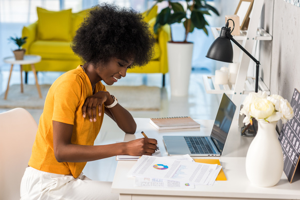 side view of smiling african american female freelancer working at home - Photo, Image