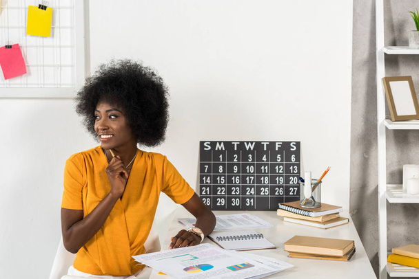glimlachen van Afro-Amerikaanse freelancer kijken weg werkplek thuis kantoor - Foto, afbeelding