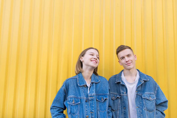 Портрет молодой пары на фоне желтой стены. Стильные мужчина и девушка на желтом фоне и улыбаются. Счастливые молодые хипстеры
 - Фото, изображение