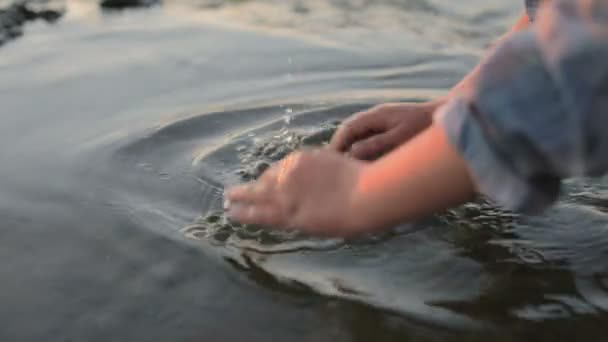 A little girl splashing sea water by the sea coast. Close-up. Sunset at the sea. - Footage, Video