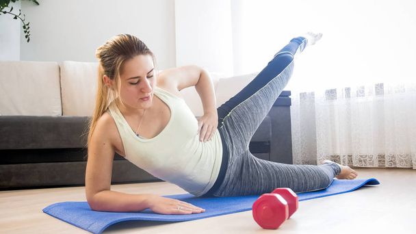 Young woman deeply breathing while doing fitness exercise at home - Foto, Bild
