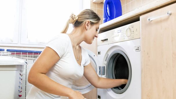 Πορτρέτο του όμορφη νεαρή νοικοκυρά χρησιμοποιώντας το πλυντήριο - Φωτογραφία, εικόνα