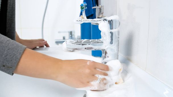 Фото крупным планом женской руки, промывающей кран с моющим средством
 - Фото, изображение
