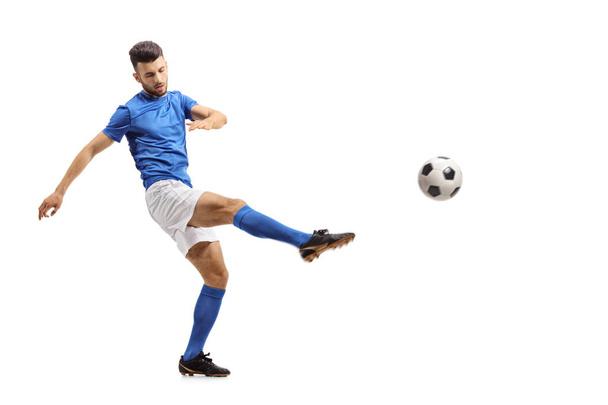 Full length portrait of a soccer player kicking a football isolated on white background - Valokuva, kuva