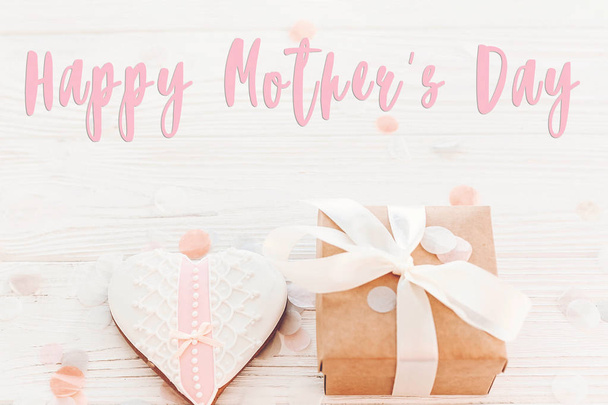 rosa glücklich Muttertag Text mit Keks Herz mit Geschenkschachtel auf weißem rustikalem Holzhintergrund - Foto, Bild