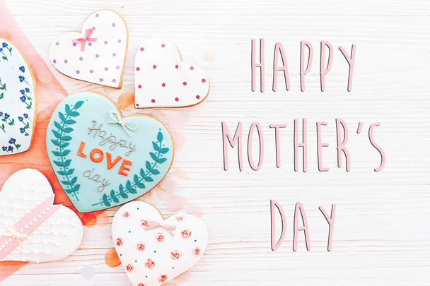 happy mothers day text with pink cookies hearts on white rustic wooden background with confetti in soft light. - Photo, Image