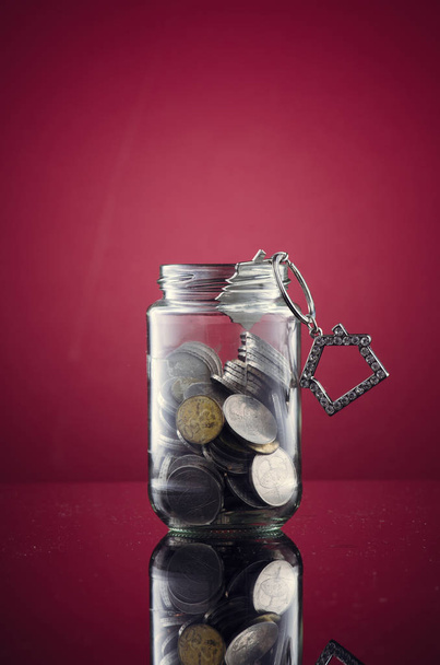 coin in transparent glass jar over red background for financial concept - Fotoğraf, Görsel
