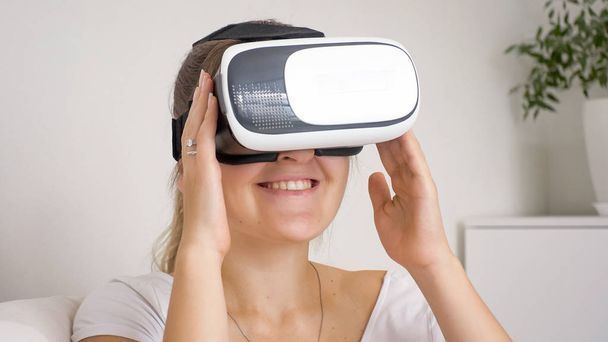 Портрет улыбающейся молодой женщины с VR гарнитурой, смотрящей фильмы
 - Фото, изображение