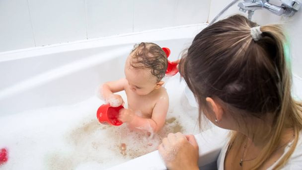 Young mother washing her toddler son in bath - Foto, Imagem