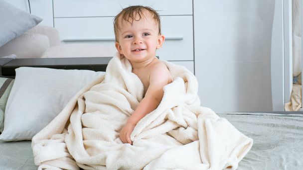 Retrato de niño alegre cubriendo con toalla blanca después de bañarse
 - Foto, imagen