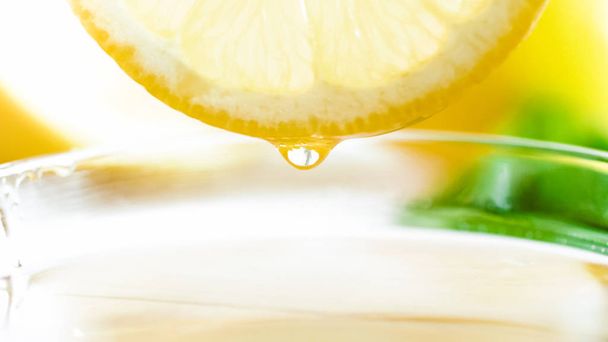 Macro foto van citroen sap druppel vallen in kopje thee - Foto, afbeelding