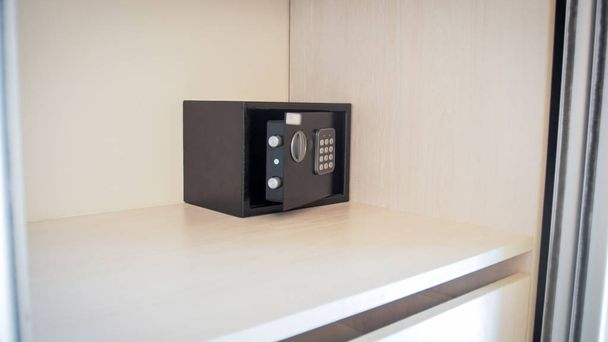 Closeup image of small open safe box in hotel room - Photo, Image