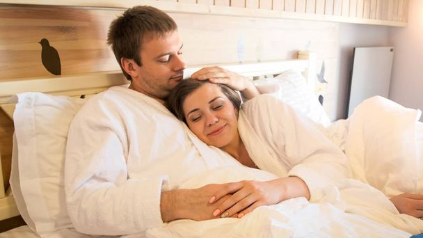 Porträt eines schönen jungen Paares, das im Bett liegt und sich umarmt - Foto, Bild