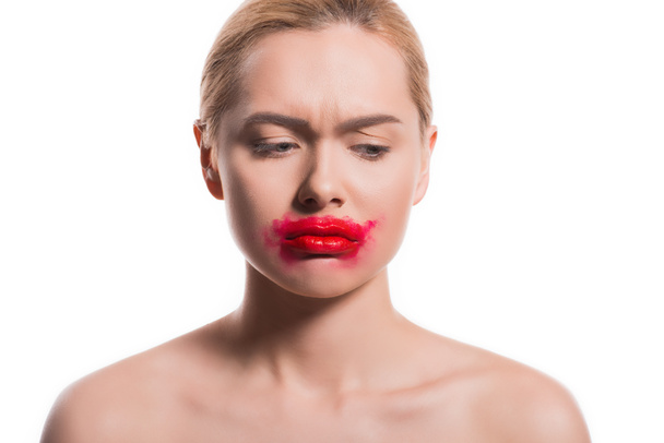 upset woman with smeared red lipstick on face looking down isolated on white - Фото, изображение