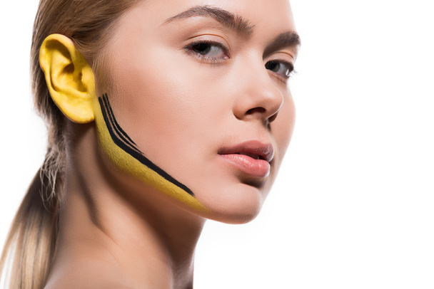 beautiful woman with yellow and black paints on ear and face isolated on white - Fotoğraf, Görsel