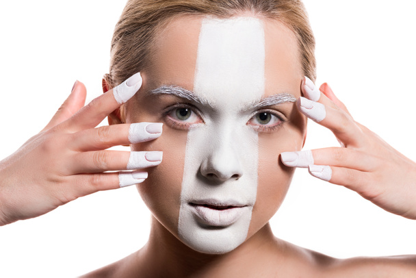 attractive woman with white paint on face and fingers looking at camera isolated on white - 写真・画像