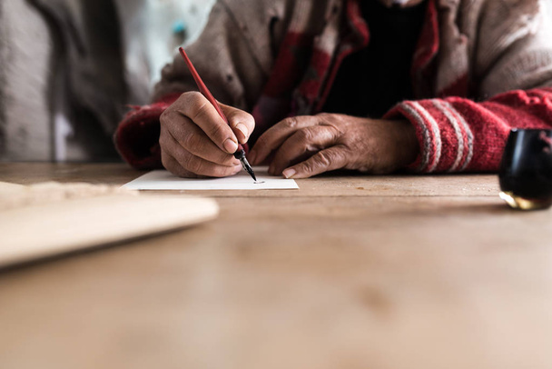 Vieil homme aux mains sales écrivant une lettre à l'aide d'un stylo plume et dans
 - Photo, image
