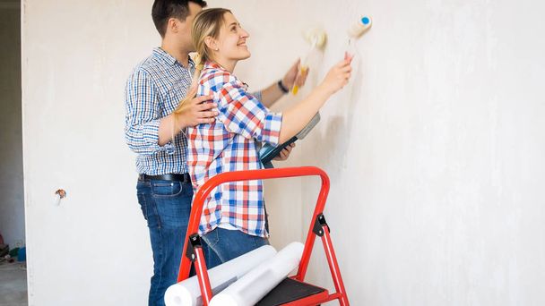 Porträt eines lächelnden Ehepaares bei Renovierungsarbeiten in einer neuen Wohnung - Foto, Bild