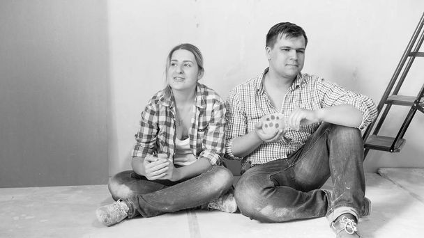 Czarno-biały obraz z młoda para siedzi na piętrze po remoncie domu - Zdjęcie, obraz
