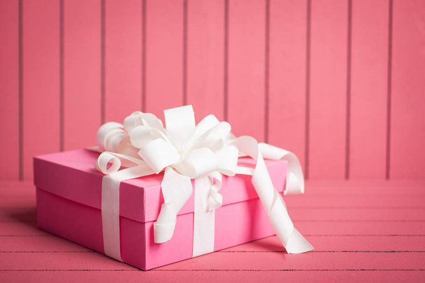 Boîte cadeau rose avec ruban blanc et noeud sur fond rose
 - Photo, image