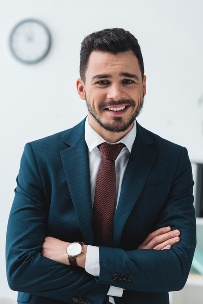 portrait of handsome young businessman with crossed arms smiling at camera - Foto, Imagem
