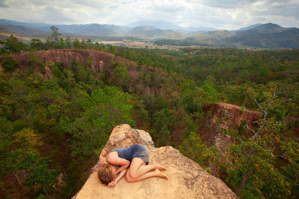 Young girl lying on top of the rock in the canyon, picture of loneliness. - Photo, Image